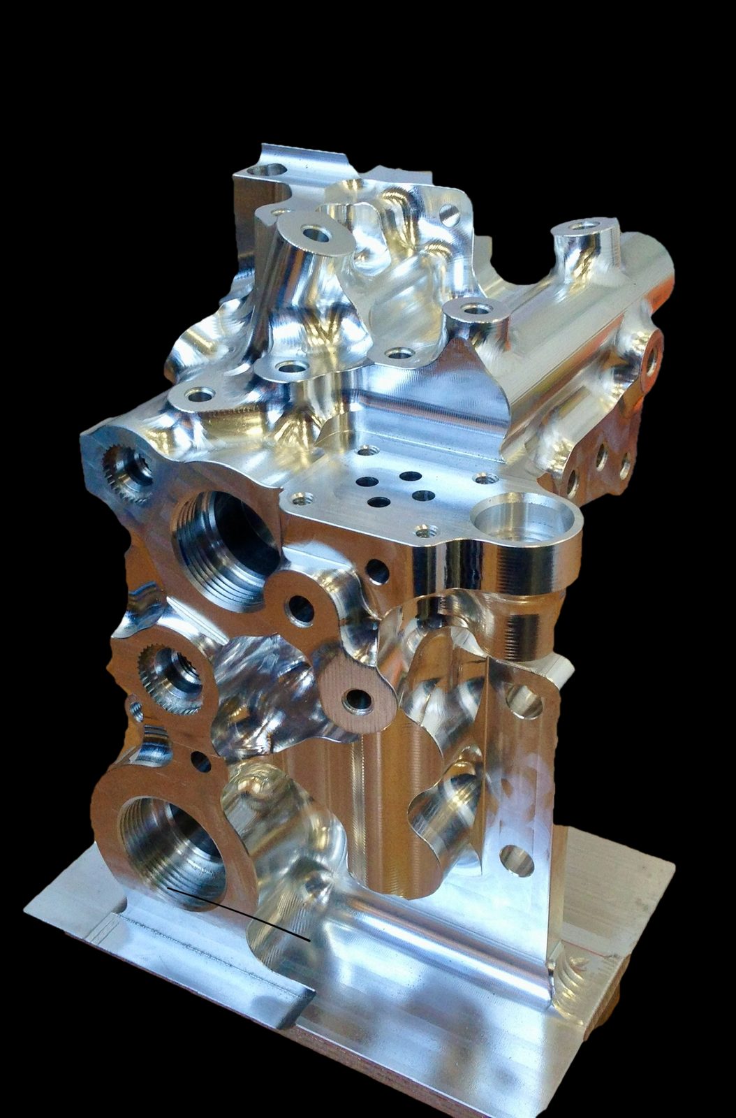 Machined aluminum manifold block with threaded ports, on a black background