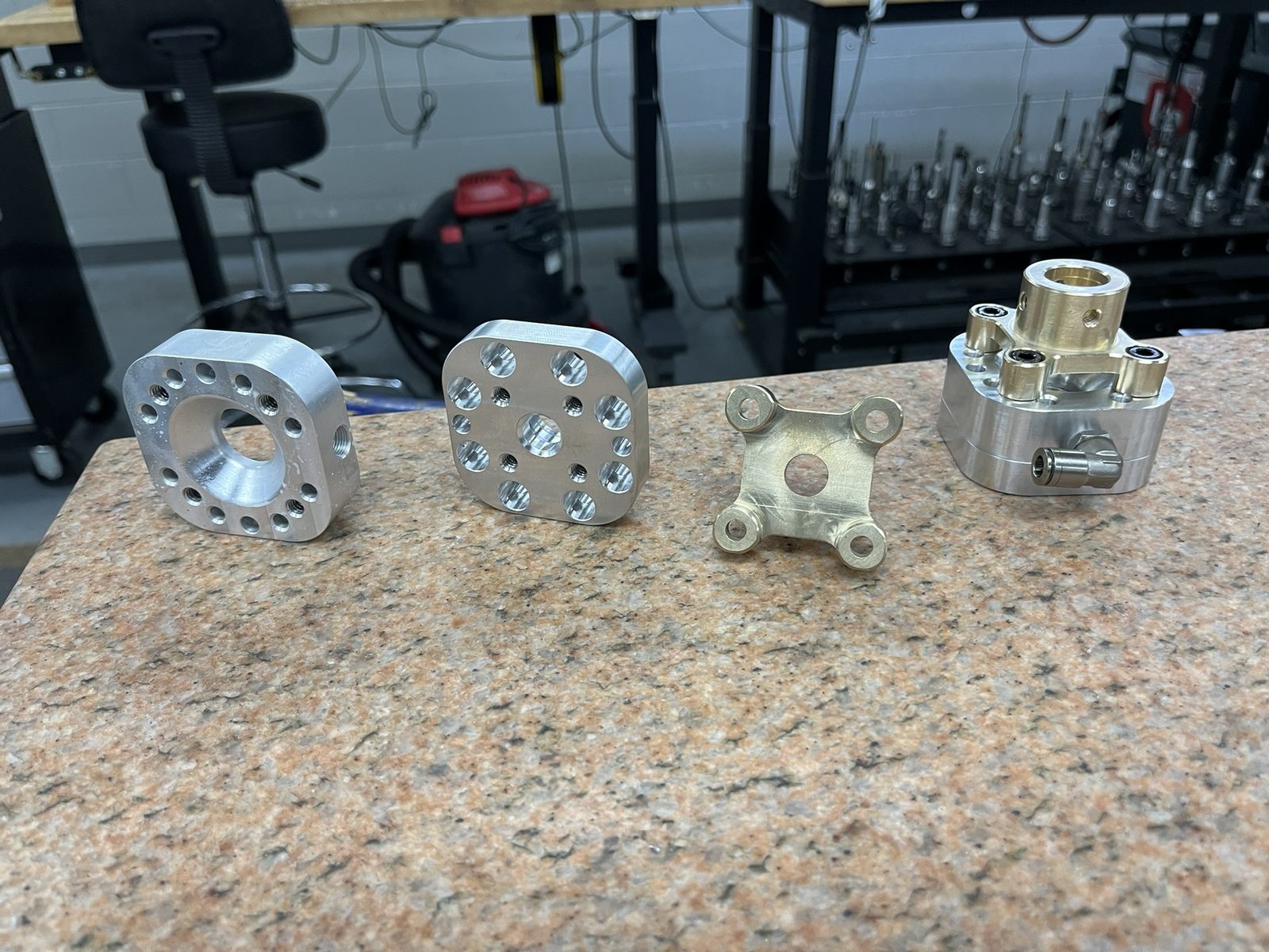 Pneumatic oil removal device: machined aluminum and brass parts on a granite surface plate